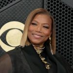 Queen Latifah smiling with a sleek blonde bob hairstyle and gold necklace against a dark backdrop
