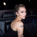 Miley Cyrus looking over her shoulder while sitting in the back of a car