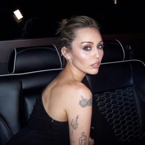 Miley Cyrus looking over her shoulder while sitting in the back of a car