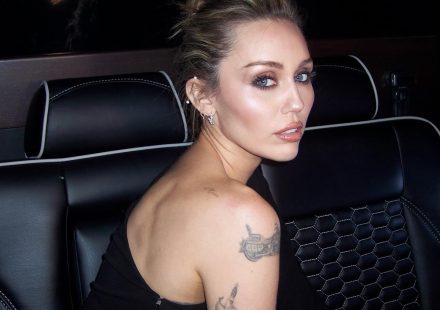Miley Cyrus looking over her shoulder while sitting in the back of a car