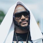 2Baba with a beard wearing large dark sunglasses, a gold chain, and a white towel draped over his head