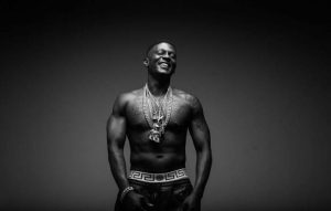 Boosie Badazz smiling and shirtless while wearing several heavy chains in a black and white portrait