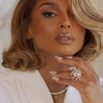 Ciara with styled blonde hair and glamorous makeup, showcasing a large diamond ring