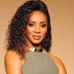 MC Lyte with curly, highlighted brown hair wearing smoky eye makeup and a gold choker necklace