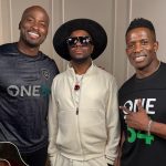 Wyclef Jean with two men (the co-hosts) wearing One54 Africa Podcast shirts