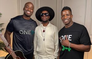 Wyclef Jean with two men (the co-hosts) wearing One54 Africa Podcast shirts