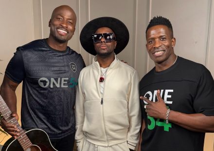 Wyclef Jean with two men (the co-hosts) wearing One54 Africa Podcast shirts