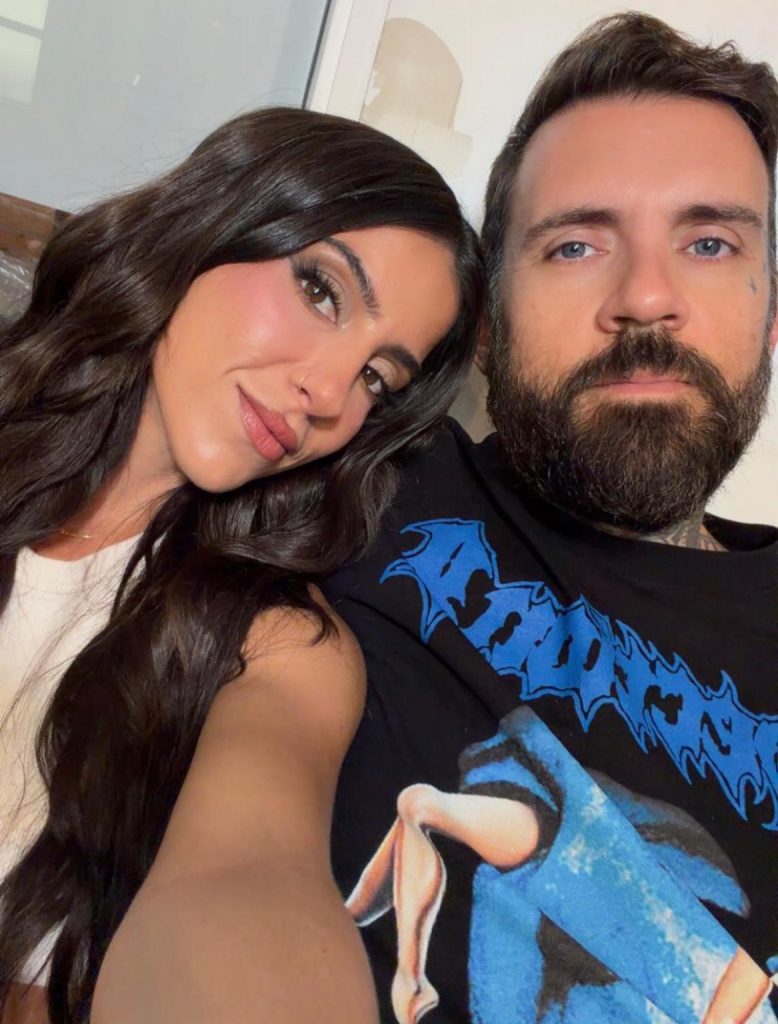 Lena the Plug smiling with long dark wavy hair leaning close to her husband Adam22 with blue eyes