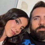 Lena the Plug smiling with long dark wavy hair leaning close to her husband Adam22 with blue eyes