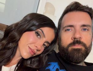 Lena the Plug smiling with long dark wavy hair leaning close to her husband Adam22 with blue eyes
